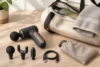 Compact massage device with three attachments, a charging cable and travel pouch beside a gym bag.